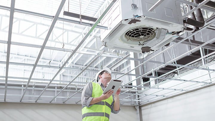 Un uomo in attrezzatura di sicurezza ispeziona un condotto di aerazione industriale