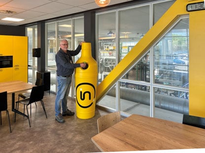 Man standing next to plastic recycling bin