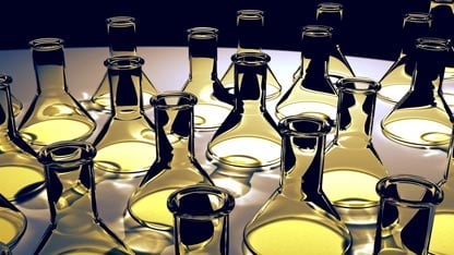 Collection of clear Erlenmeyer flasks on a black background with yellow light reflecting