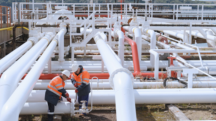 Alcuni uomini lavorano nei pressi di alcune tubature di una raffineria