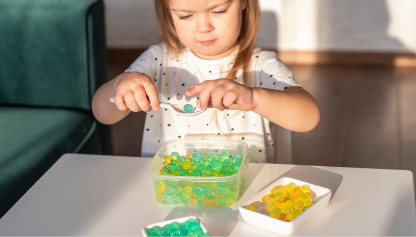 Little girl playing with sensory water beads, hydrogel balls.