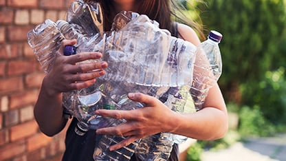 una donna con molte bottiglie di plastica