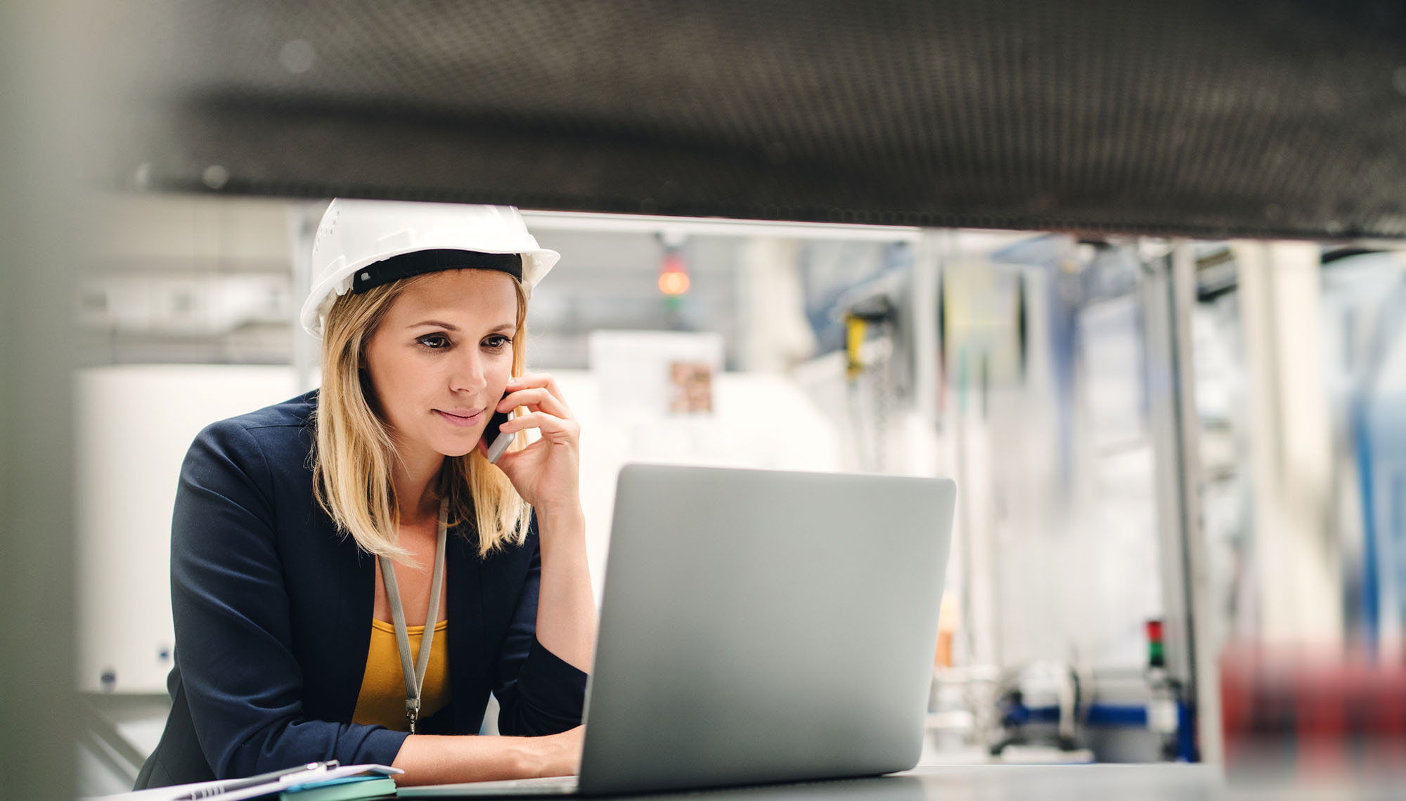 Woman wearing hard hat on computer.