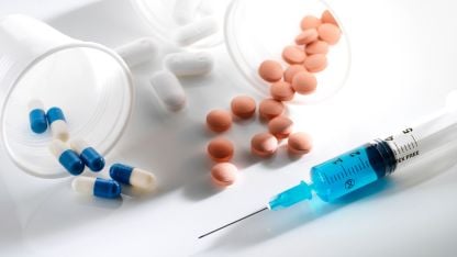 A close-up image featuring various pills alongside a syringe, illustrating medical supplies and health-related themes.