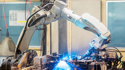 Welding industrial robotic welding machines in operation in a metal manufacturing plant