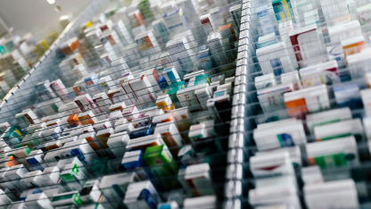 Rows of labeled prescription medication boxes organized neatly in a modern pharmacy storage system