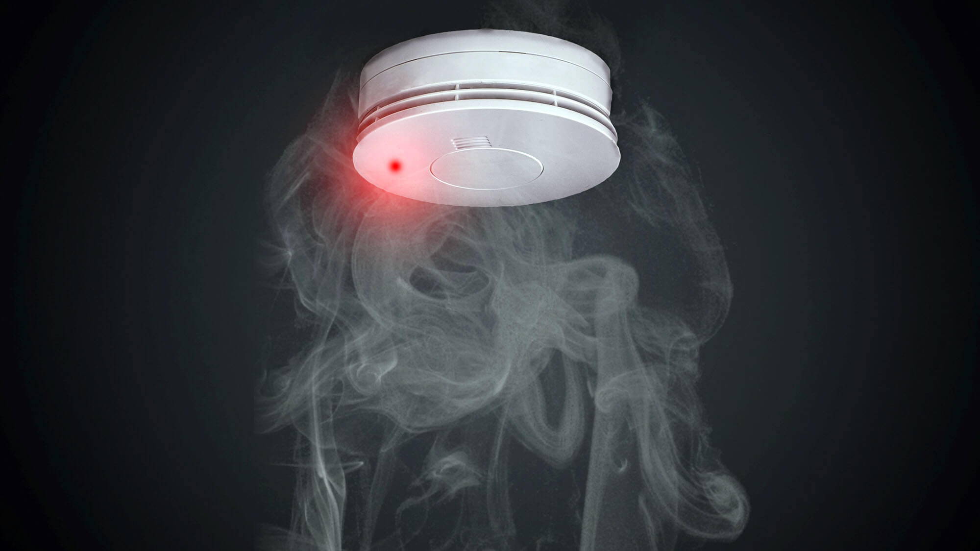 Smoke detector on black background with smoke rising