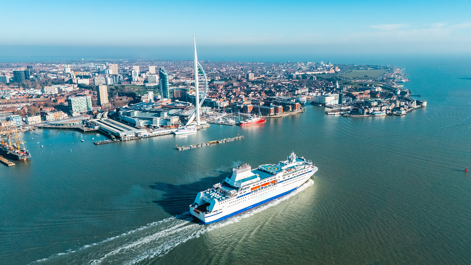 Harbour in the UK with buildings along the waterfront and a ferry boat moving across the water